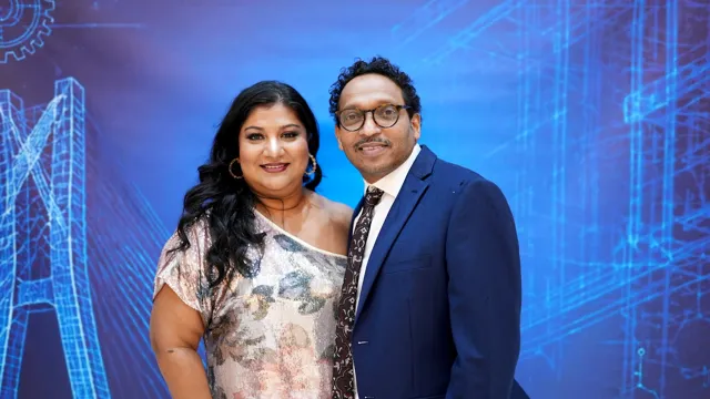 A couple posing in front of the event backdrop